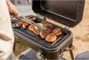 A person is grilling meat on a portable grill outdoors. Náhľad obrázku produktu