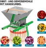 A fruit and vegetable mill with a hand crank, shown with various fruits and vegetables around it. Produktbild-Vorschau