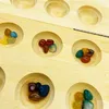 A close-up view of a wooden board game with several circular indentations filled with colorful polished stones. Produktbild-Vorschau