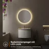 A modern bathroom vanity with a round LED mirror above it, featuring decorative flowers and ambient lighting. Anteprima dell’immagine prodotto