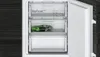 An open refrigerator freezer with drawers, one containing a bag of green vegetables. Voir les images du produit