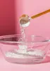 Powder being scooped from a wooden spoon into a glass bowl with liquid. Produktbild-Vorschau