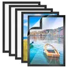 A stack of black picture frames with a colorful image of a coastal town and boats visible in the front frame. Anteprima dell’immagine prodotto