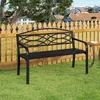 A black metal garden bench sits on a green lawn in front of a wooden fence, with houses visible in the background. Produktbild-Vorschau