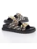 A pair of black and gold Guess Fatema Pantolette sandals are displayed on a white background. Podgląd zdjęcia produktu