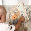 A baby is playing with a wooden activity tree toy. Produktbild-Vorschau
