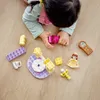 A child playing with LEGO DUPLO bricks on a wooden floor. Podgląd zdjęcia produktu