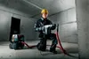 A construction worker is using a rotary hammer drill with a vacuum attachment in a concrete room. Náhľad obrázku produktu