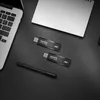 A black desk with a laptop, two USB flash drives, a notebook, and a pen. Anteprima dell’immagine prodotto