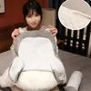 Frau hält ein graues und weißes ergonomisches Rückenstützkissen mit strukturierter Oberfläche, daneben ein passendes Nackenrollenkissen Náhled obrázku produktu