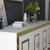 A close-up view of a white sideboard with gold accents, featuring decorative elements and books on top. Produktbild-Vorschau