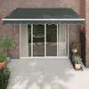 An awning is extended over a sliding glass door on a brick wall, with a patio in front. Anteprima dell’immagine prodotto