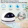 A mini desktop vacuum cleaner is shown on a wooden table, with colorful confetti scattered in front of it, being cleaned up by the vacuum. Feature icons and text are displayed above the vacuum. Produktbild-Vorschau