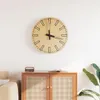 A wooden wall clock with a minimalist design is mounted on a white wall above a wooden cabinet. Náhled obrázku produktu