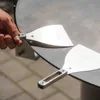 A hand holding a metal spatula over a round metal surface, with another spatula visible on the surface. Podgląd zdjęcia produktu