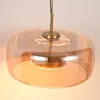 Close-up of a modern pendant light with a translucent amber glass shade and a metallic gold ring. Anteprima dell’immagine prodotto