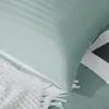 A close-up view of a sage green striped pillowcase and a white textured blanket. Podgląd zdjęcia produktu