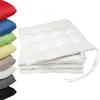 A stack of white seat cushions with ties, next to a stack of seat cushions in various colors. Produktbild-Vorschau
