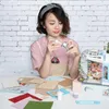A woman is assembling a miniature dollhouse. Anteprima dell’immagine prodotto