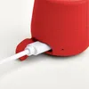 A close-up of a red Bluetooth speaker being charged by a white USB cable. Produktbild-Vorschau