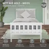 A white wooden bed with pillows and a rug in a room with a light green wall. Náhled obrázku produktu