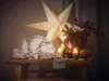 A festive table setting with Christmas-themed tableware, candles, and a large illuminated star. Produktbild-Vorschau
