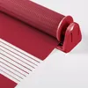 A close-up view of a red roller blind, showing its textured fabric and the mechanism for rolling it up. Produktbild-Vorschau