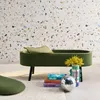 A green bouclé bench with a pillow and decorative items on a rug in front of a terrazzo wall. Produktbild-Vorschau