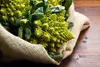 A close-up of Romanesco broccoli in a burlap sack on a wooden surface. Voir les images du produit