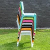 A stack of colorful chairs outdoors in front of a brick wall. Produktbild-Vorschau