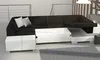A sectional sofa with a pull-out section and storage. The sofa is black with white stitching and white storage ottomans. It is placed on a gray rug in a room with a modern aesthetic. Náhled obrázku produktu