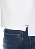 Close-up of the bottom hem of a white polo shirt worn over blue jeans. Produktbild-Vorschau