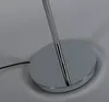 Close-up of the base of a floor lamp, showing the chrome-plated steel base and a black power cord. Produktbild-Vorschau