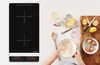 A person is preparing ingredients for baking next to an induction cooktop. Voir les images du produit