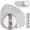 A set of gray placemats with a plate, napkin, and cutlery arranged on one of them. There are also several napkin rings and a stack of placemats in the background. Produktbild-Vorschau