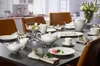 A dining table set for a tea party with white porcelain dishes, teapots, cups, and pastries. Náhľad obrázku produktu