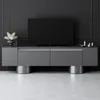 A modern TV stand with a television and decorative items in a minimalist room. Voir les images du produit
