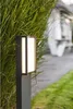 A modern outdoor LED path light is positioned next to lush green foliage, with a blurred pathway and building in the background. Anteprima dell’immagine prodotto