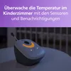 A Philips AVENT baby monitor is shown on a table in a dimly lit room, with a purple overlay at the top containing text. Produktbild-Vorschau
