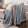 A gray blanket draped over a sofa with a pillow. Produktbild-Vorschau