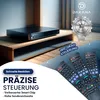 A black electronic device is placed on a wooden shelf, with several remote controls in the foreground. Produktbild-Vorschau