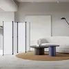 A modern living room with a white sofa, coffee tables, and a room divider. Produktbild-Vorschau