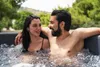 A couple relaxing in an outdoor hot tub surrounded by greenery. Náhled obrázku produktu