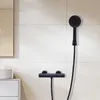 A black shower fixture and handheld showerhead mounted on a tiled wall. Produktbild-Vorschau