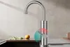 A modern kitchen faucet with a curved spout and a single lever handle, shown in a kitchen setting with a sink and countertop. There are some green sprigs and a lemon on the countertop. Podgląd zdjęcia produktu