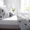 A close-up view of a bed with white bedding featuring a winter-themed pattern of green and gray trees and snowflakes. Produktbild-Vorschau