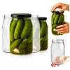 Several glass jars filled with pickles are arranged on a white background. One jar is being held by a hand, and another empty jar is shown separately. Podgląd zdjęcia produktu
