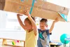 Two children carrying a large cardboard box. Produktbild-Vorschau