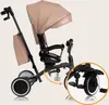 A beige and black Lionelo Tris Plus tricycle is shown against a white background. A close-up inset highlights the rear wheel and pedals. Podgląd zdjęcia produktu