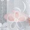 A hand is shown reaching through a white lace curtain with a floral pattern. Náhled obrázku produktu